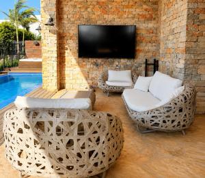 a living room with two wicker chairs and a tv at Casa del Barone - וילה יוקרתית עם בריכה פרטית in Kefar Tavor