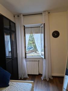 a room with a window with white curtains and a clock at Home G & D in Monza
