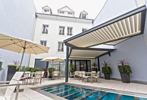 a patio with a swimming pool and a building at Le Rex Hôtel in Tarbes
