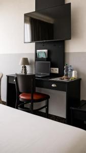 a desk with a laptop and a chair in a room at Hôtel-Restaurant La Belle Poule - in Rochefort +18 photos