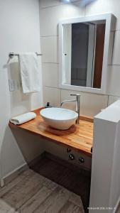 a bathroom with a white bowl sink on a wooden counter at Cabañas Altos del Sauce in Villa General Belgrano +23 photos