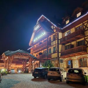 two cars parked in front of a hotel at night at Hotel Kukučka Apartment C104 Tatranská Lomnica in Vysoké Tatry