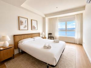 a bedroom with a large white bed and a window at Blue Ocean Deluxe in Sanxenxo