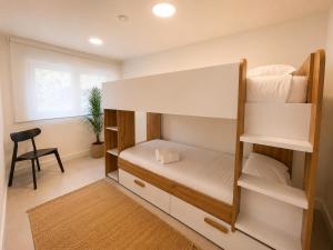 a bedroom with a bunk bed with a chair and a window at Blue Ocean Deluxe in Sanxenxo +7 photos
