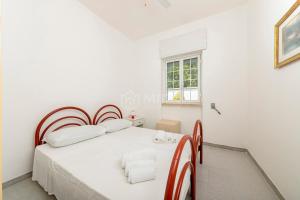 a white bedroom with a bed and a window at Villa Cesare in Torre Specchia Ruggeri