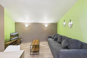 a living room with a couch and a tv at Le Cocoon Fuchsia in Romilly-sur-Seine