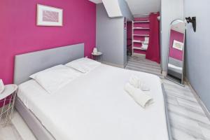 a bedroom with a white bed and a pink wall at Le Cocoon Fuchsia in Romilly-sur-Seine +8 photos