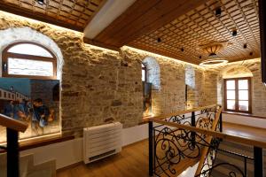 a room with a stone wall with windows and a staircase at Hotel Kashah in Gjirokastër