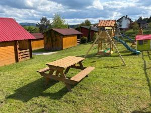a park with a wooden bench and a playground at POD FALAMI - domki letniskowe in Polańczyk
