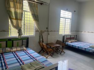 a room with two beds and a table and chairs at Mecong Homestay in Ben Tre