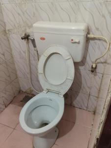 a bathroom with a white toilet with the lid up at R K Residency Formerly Gamas in Trivandrum