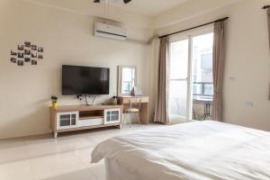 a white bedroom with a tv and a bed at Beyond Home in Jiaoxi