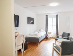 a bedroom with a bed and a couch and a chair at Hotel Weisses Kreuz in Interlaken