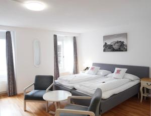 a bedroom with a large bed and a chair at Hotel Weisses Kreuz in Interlaken