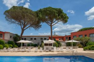 a pool with white chairs and umbrellas and tables at Salles Hotel Aeroport de Girona in Riudellots de la Selva