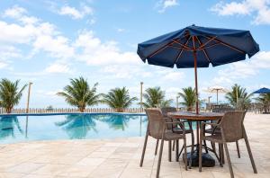 a table with an umbrella next to a swimming pool at Maragogi Praia Hotel in Maragogi