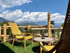 a patio with two chairs and a table in the grass at Agriturismo Ortesida in Morbegno