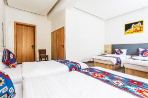 a hotel room with two beds and a desk at Solief Hotel in Tashkent