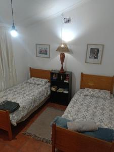 a bedroom with two beds and a table with a lamp at Skaap Kraal Guest Farm in Kakamas