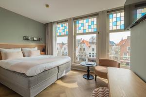 a bedroom with a large bed and large windows at City Hotel Rembrandt in Leiden