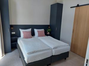 a bedroom with a large bed with pink and white pillows at Comfort bungalow 02 met jacuzzi in Putten