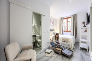 a woman sitting on a suitcase in a bedroom at Password to Madrid Gran Vía in Madrid