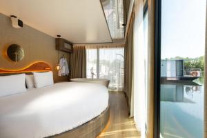 a bedroom with a white bed and a large window at L'Escale Royale Torcy - Marne la Vallée in Torcy
