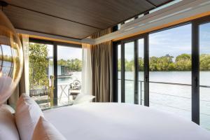 a bedroom with a large bed and large windows at L'Escale Royale Torcy - Marne la Vallée in Torcy
