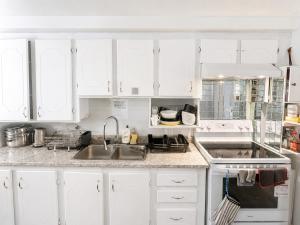 a kitchen with white cabinets and a sink at Louisbourg room & Aurora House in Glace Bay