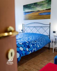 a blue bed in a room with a painting on the wall at Agriturismo La Valle del Vento Urbino in Urbino +76 photos