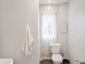 a white bathroom with a toilet and a window at Màple room & Aurora House in Glace Bay