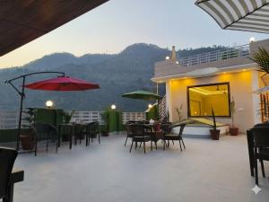 a patio with tables and chairs and umbrellas at Jayati Palace Hotel in Rudraprayāg