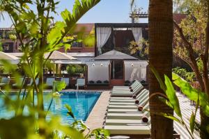 a pool with lounge chairs next to a resort at Hôtel & Ryads Barrière Le Naoura in Marrakesh