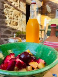 a bowl of fruit on a table with a bottle of orange juice at Chez TROTRO in Saint-Pierre-de-Plesguen