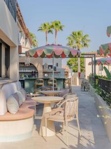 a patio with tables and chairs and an umbrella at Capucines Hotel Saint Tropez in Saint-Tropez