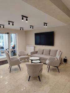 a living room with a couch and chairs and a flat screen tv at Alen Mak in Govedartsi