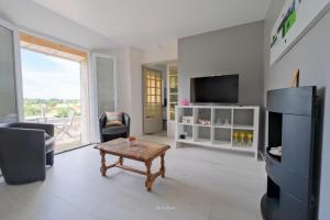 a living room with a table and a tv at La Maison Jopateliére in Mohon