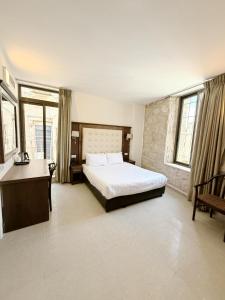 a bedroom with a bed and a desk and windows at The Annexe - by Gloria Hotel in Jerusalem +10 photos