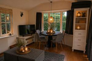 a living room with a table and a tv at Vechtdalchalet de Berk, 5 sterrenpark Capfun Stoetenslagh in Rheezerveen