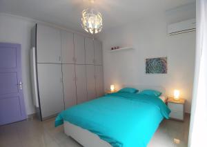 a bedroom with a blue bed and a chandelier at KYMA Apartments - Athens Acropolis 1 in Athens