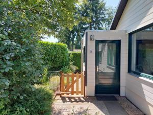 a house with a black door and a fence at Huisje nr. 18 met jacuzzi in Putten