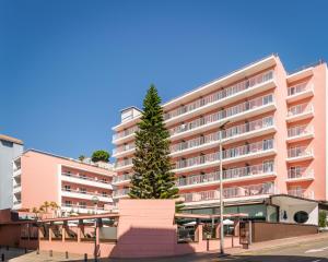 a tree in front of a pink building at The Place Mariner by ALEGRIA Adults Only in Lloret de Mar