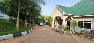 a white house with a green roof and a street at COMFORT ZONE Lodge Kigoma in Kigoma
