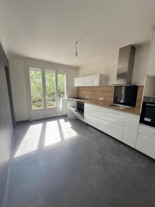 a kitchen with white cabinets and a large window at Maison rénovée Montélimar in Montélimar