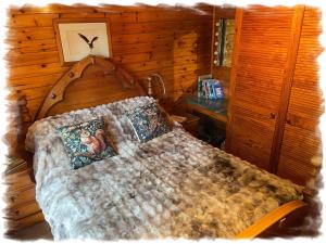 a bed in a bedroom with a wooden wall at Blelham Tarn Rustic cabin in tranquil woodland in Ambleside +35 photos