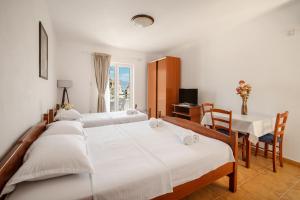 a bedroom with four beds and a table and a table and chairs at Sunset Studio Apartments Bjelila in Tivat