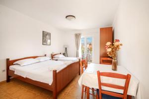two beds in a room with a table and chairs at Sunset Studio Apartments Bjelila in Tivat +12 photos