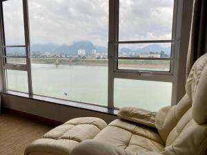 a living room with a couch and a large window at Khách sạn APPLAZA in Hòa Bình