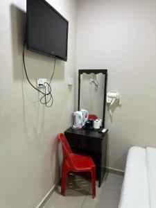 a bedroom with a red chair and a tv on the wall at Hotel Lean Fatt in Ipoh