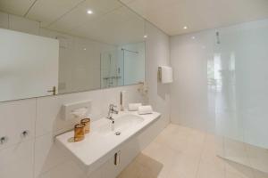 a white bathroom with a sink and a mirror at Los Lorentes Hotel Bern Airport in Belp +82 photos